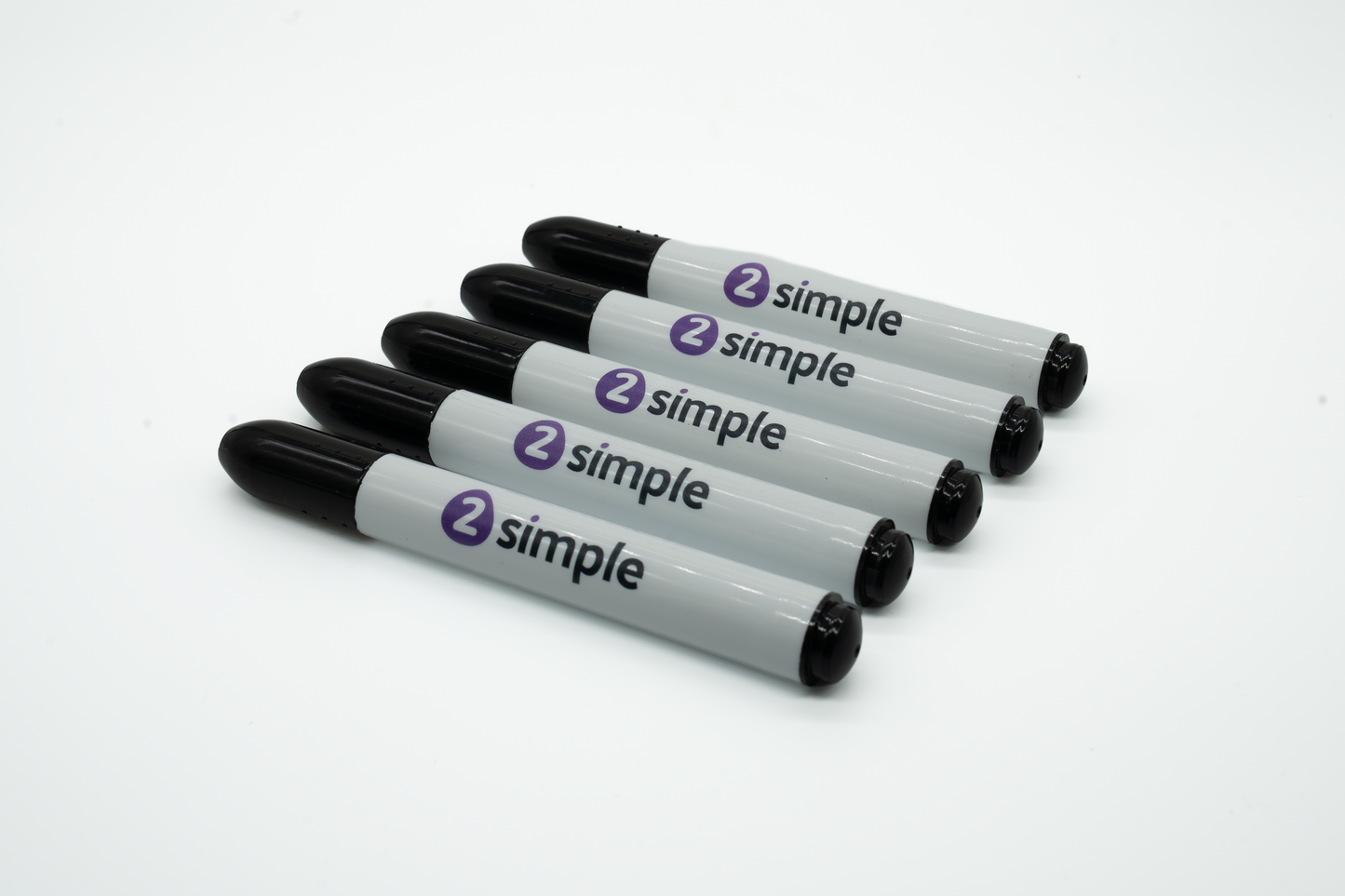 Five marker pens arranged diagonally on a plain white background. Each marker has a black cap and tip, a light gray barrel, and a purple circular logo with the word 'simple' printed in black.